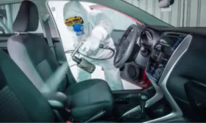 addetto alla sanificazione con dispositivi di sicurezza yuta maschera e guanti utilizza un macchinario per sanificare l'abitacolo di un'auto